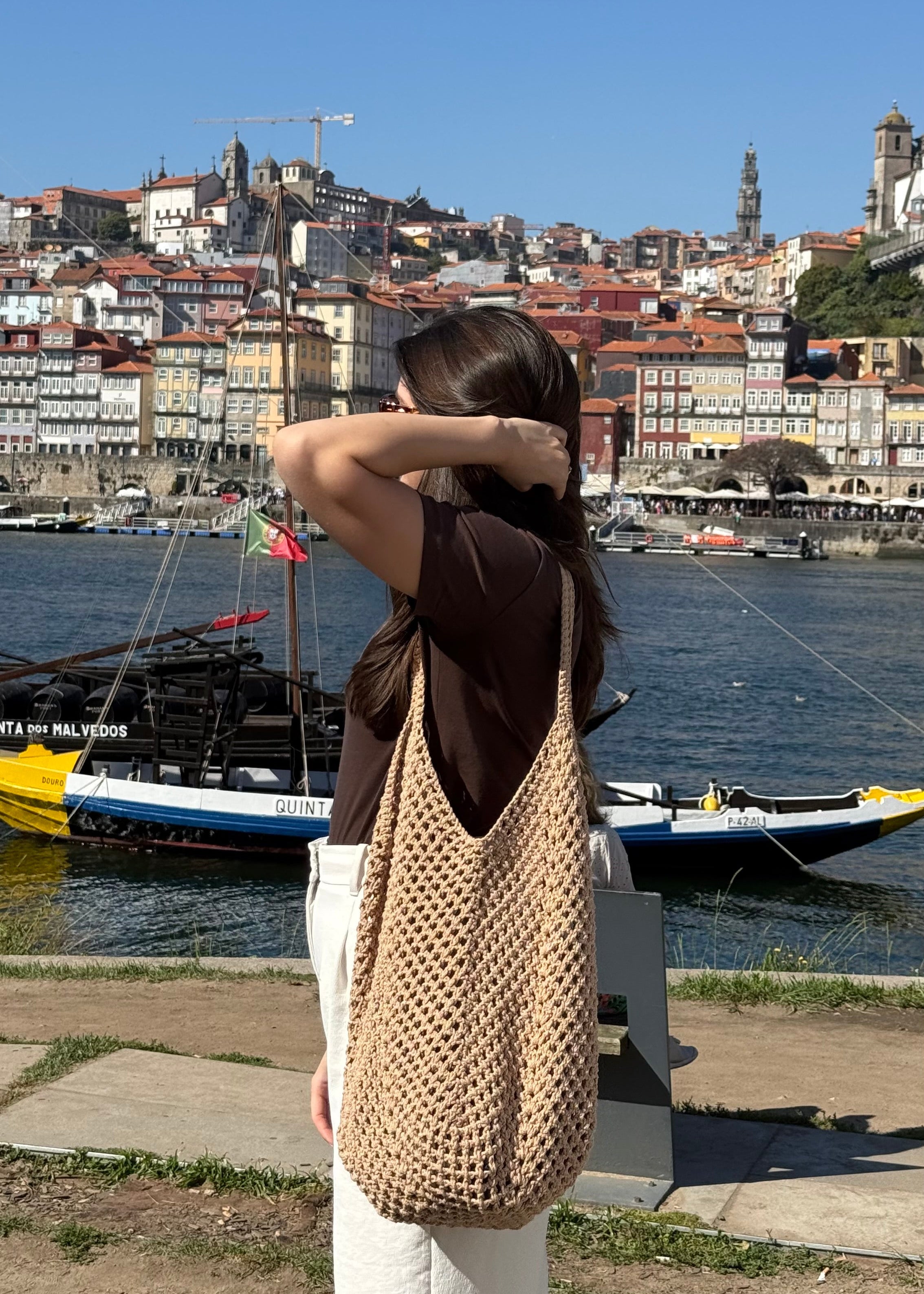 A girl with a handmade crocheted mesh tote bag standing in the city 