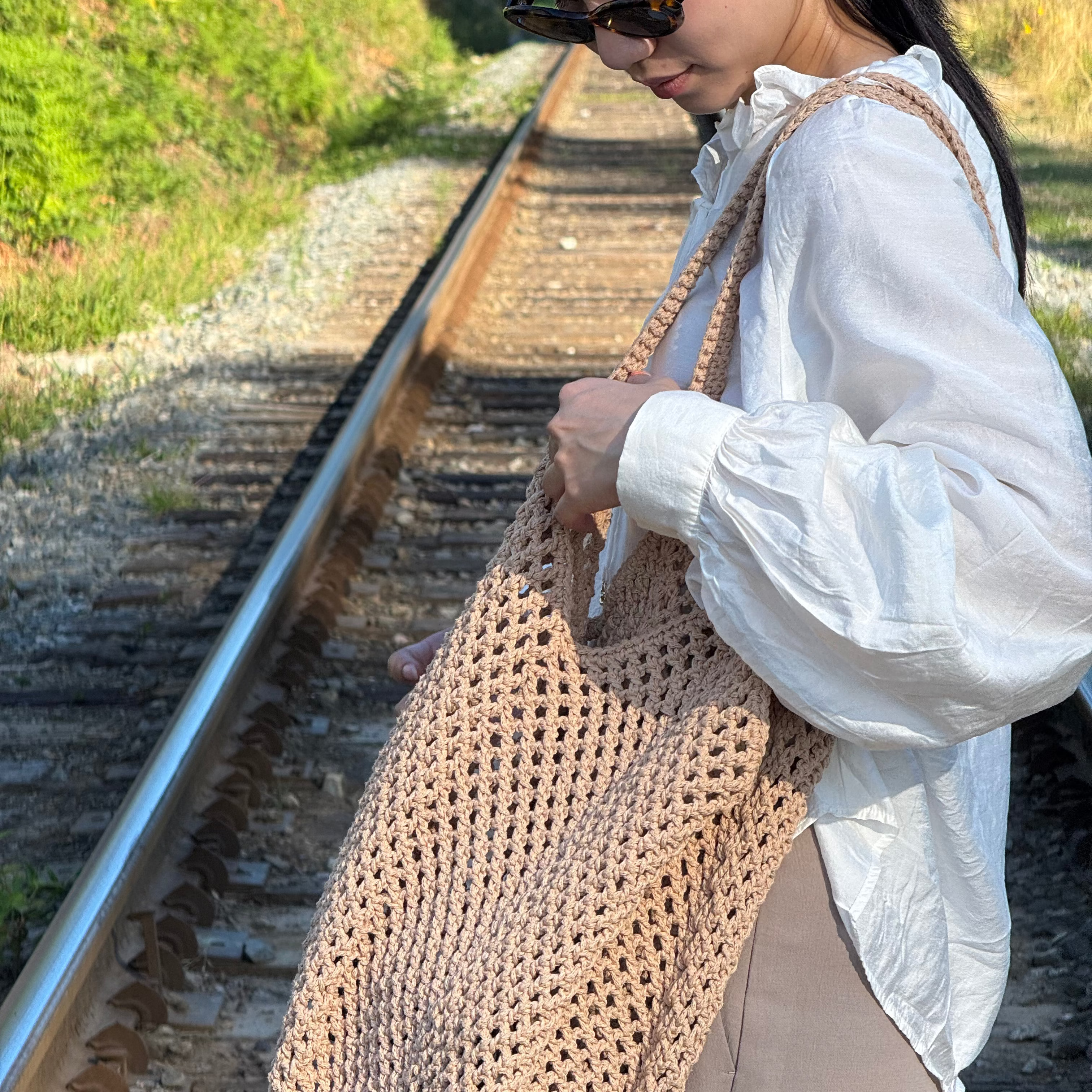 Woman holding a beige crochet bag 